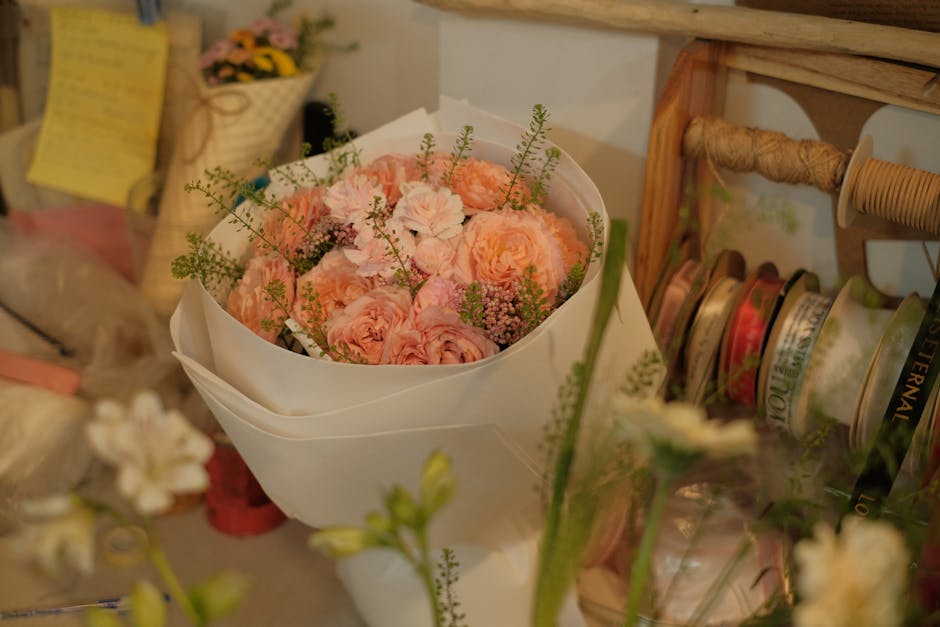 Beautiful pink flower bouquet wrapped in white paper in a cozy florist's workshop setting.