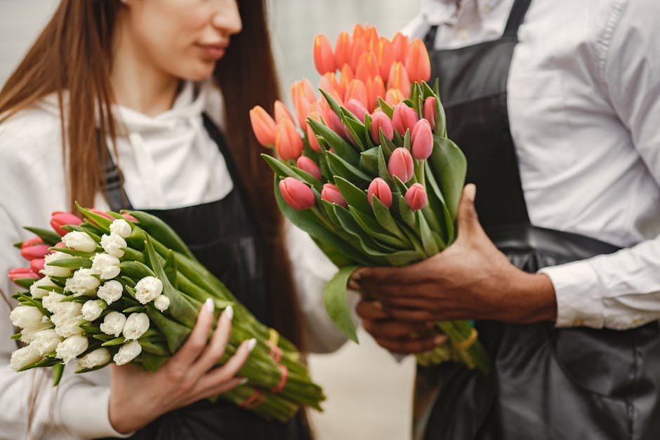 Close-up of two florists holding colorful tulip bouquets, emphasizing teamwork and floral beauty.